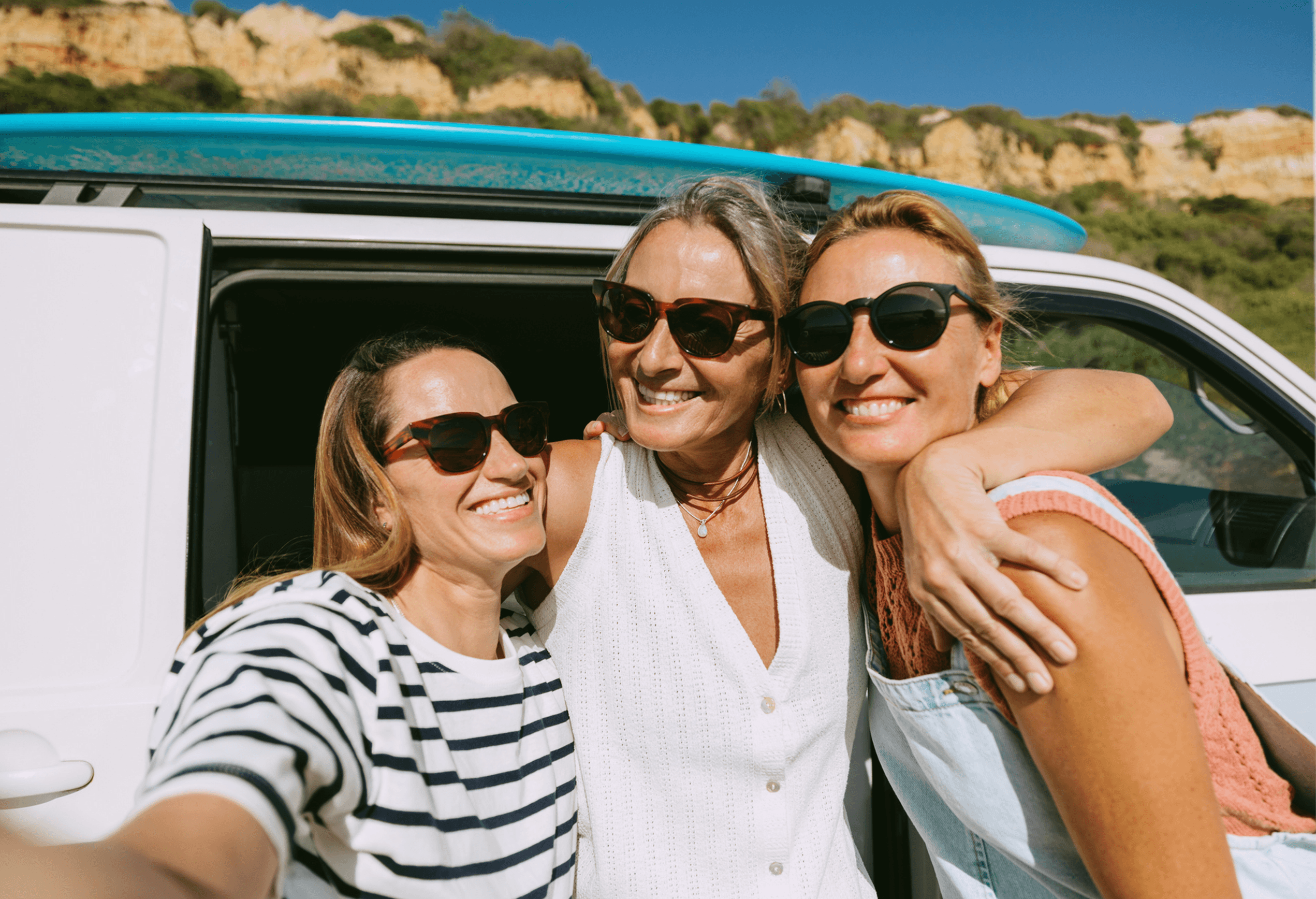 3 women posing in front of a camper van